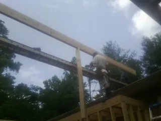 Carpenter setting a ridge beam over a new addition frame — Ice Dam Removal by Roofing Brothers in Currituck