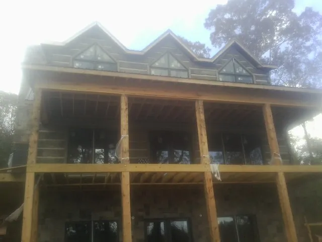 Dormers and porch framing on a large log home under construction — Roof Coating work by our crew in Currituck