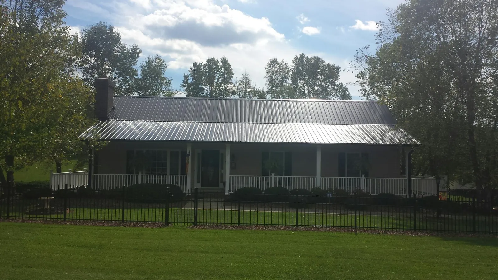 Gray metal roof on a brick ranch with a full width front porch — Gutter Guard Installation work by our crew in Currituck